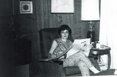 Marj in 32 McKenzie with paper, cigarette and coffee, late 1960's.